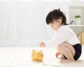 ÃÂ baby girl inserting coin into piggybank